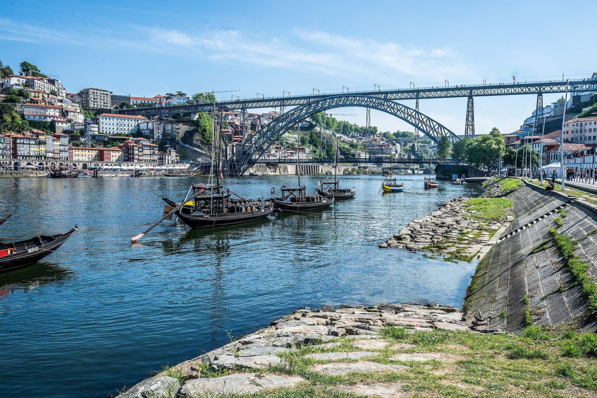 Rabelo boats moored on the Douro at Cais de Gaia with the Ribeira facades and Dom Luís I Bridge behind